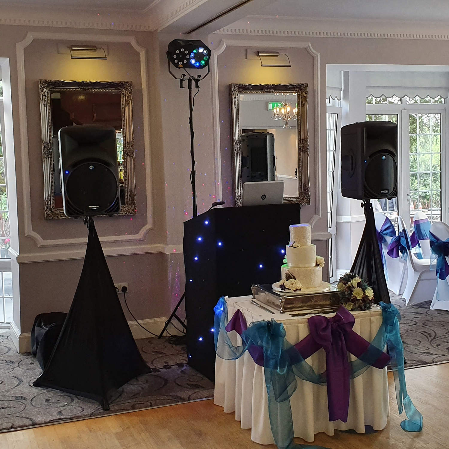 Black twinkling DJ booth behind wedding cake table on dance floor at wedding in south wales.