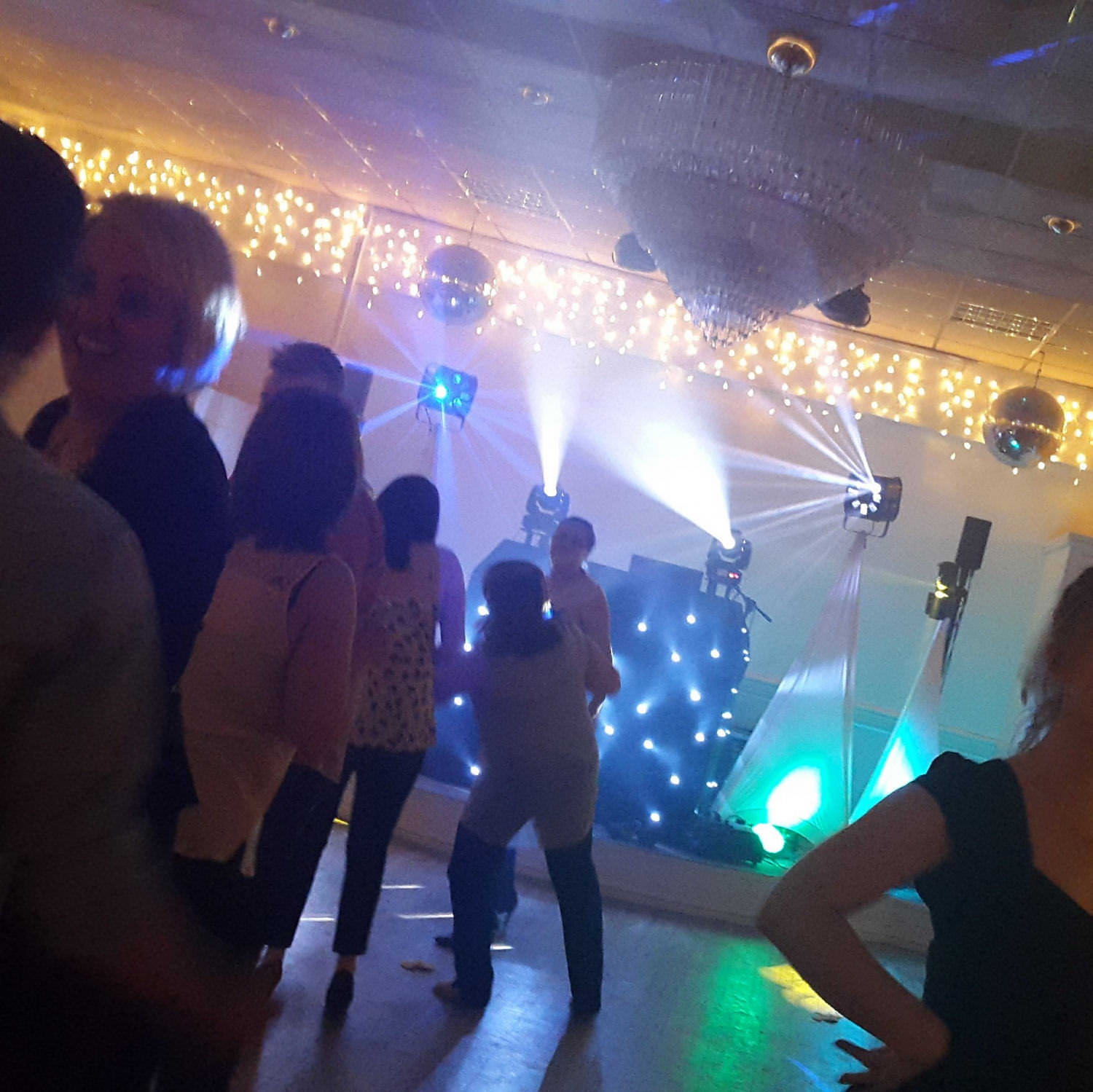 Black twinkling disco booth backlit in purple as laser patterns move over the dance floor.